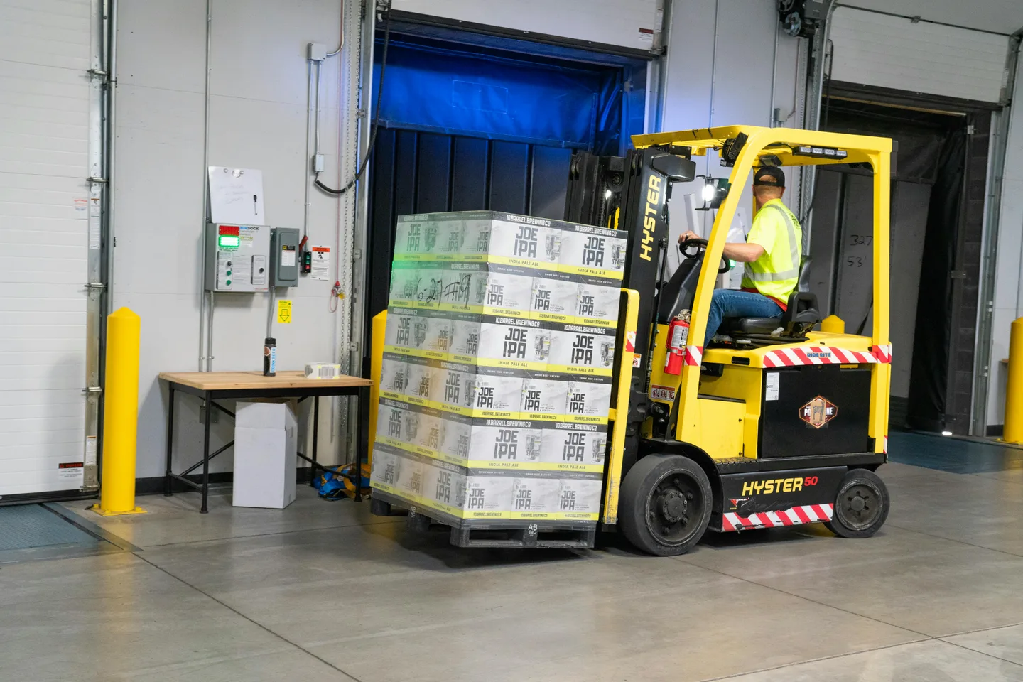 A worker reverses a forklift carring a load
