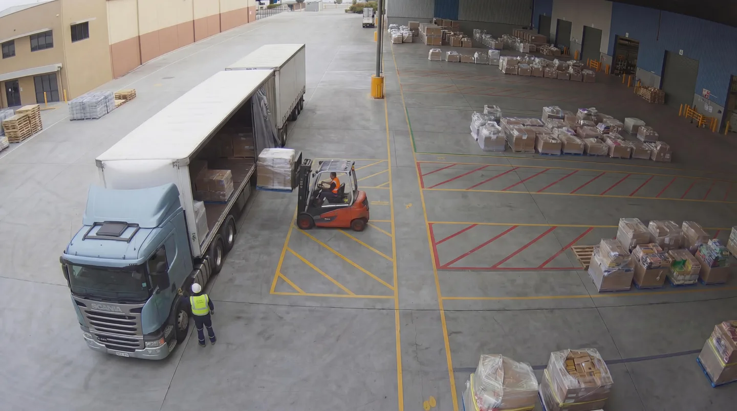 A forklift unloads a delivery truck with the driver heeding the marked exclusion zone